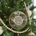 A round ornament hanging on a Christmas tree, featuring a scenic landscape with a waterfall and a cabin.
