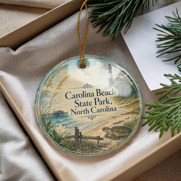 A decorative ornament with a lighthouse and beach scene, placed in a box with pine branches.