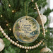 A round ornament hanging on a Christmas tree, featuring a lighthouse and a scenic landscape.