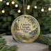 A round ornament with a lighthouse and a boat on a lake, surrounded by greenery and a string of lights.