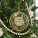 A Christmas tree decorated with ornaments, including a circular ornament with a scenic image of the Cathedral State Park in West Virginia.