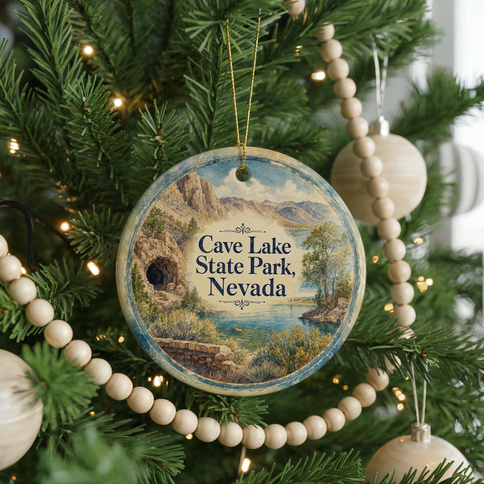 A round ornament hanging on a Christmas tree, featuring a scenic landscape with mountains, trees, and a lake.