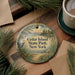 A decorative ornament with the text "Cedar Island State Park, New York" on it, surrounded by pine branches and pine needles.