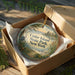 A decorative ornament in a box, featuring a scenic landscape of Cedar Island, New York.