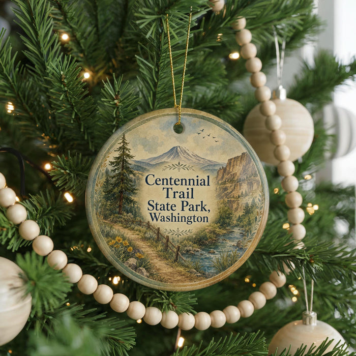A Christmas tree decorated with ornaments, including a circular ornament that says "Centennial Trail State Park, Washington".