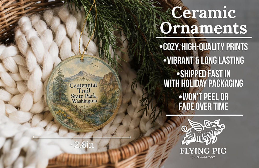 Ceramic ornaments, featuring a scenic image of the Centennial Trail State Park, Washington, with a wicker basket and greenery in the background.