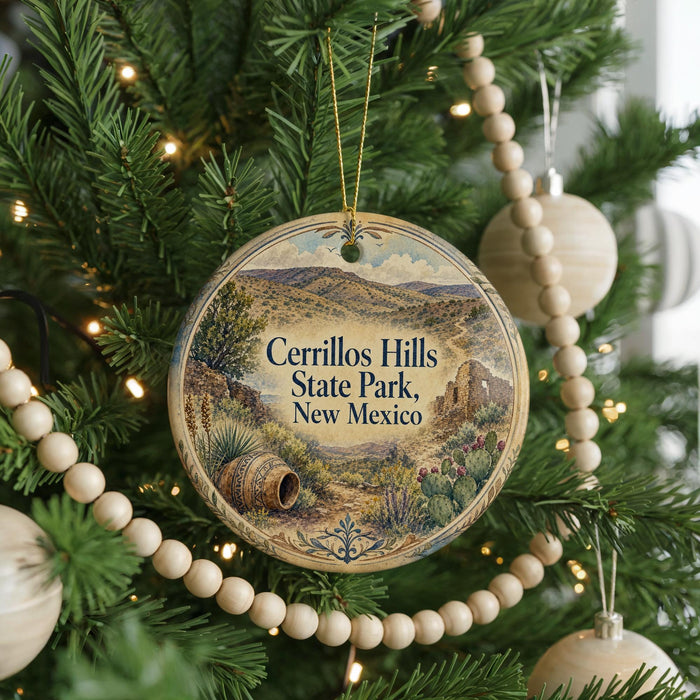 A round ornament hanging on a Christmas tree, featuring a scenic landscape of hills and a desert.