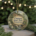 A round ornament with a scenic image of Chapman State Park in Pennsylvania, featuring a waterfall and forest, is displayed against a blurred background of Christmas lights.
