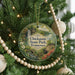 A round ornament hanging on a Christmas tree, featuring a scenic landscape with a waterfall and a bridge.