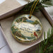 A decorative ornament with a scenic landscape of Chief Logan State Park, West Virginia, featuring a bird, pine trees, and a waterfall.