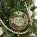 A round ornament hanging on a Christmas tree, featuring a scenic landscape with a waterfall and a red cardinal perched on a branch.