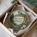 A decorative ornament in a box, featuring a scenic landscape with mountains, a waterfall, and flowers.
