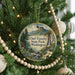 A round ornament on a Christmas tree, featuring a scenic landscape with mountains, trees, and a waterfall.