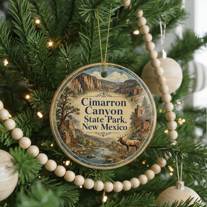 A round ornament hanging on a Christmas tree, featuring a scenic image of Cimarron Canyon State Park in New Mexico.