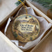 A decorative ornament in a box, featuring a scenic landscape with mountains, trees, and a desert-like environment.