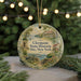A decorative ornament featuring a scenic landscape with a house, trees, and a body of water, hanging on a string.