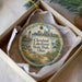 A decorative ornament in a box, featuring a scenic view of Cleveland, Ohio, with a lighthouse and a boat on the water.