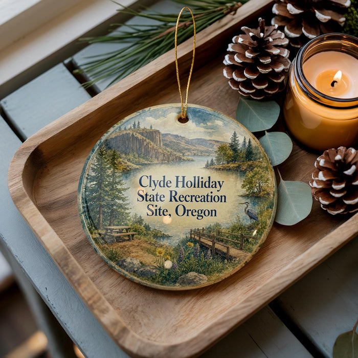 A wooden tray with a decorative ornament featuring a scenic landscape, pine cones, and a lit candle.