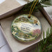 A decorative ornament in a box, featuring a landscape with a house, flowers, and a man, along with text that reads "Cordell Hull Birthplace State Park, Tennessee".