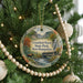 A round ornament hanging on a Christmas tree, featuring a scenic image of a bridge and mountains in New Hampshire.