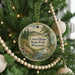 A round ornament hanging on a Christmas tree, featuring a scenic landscape with a river and mountains.