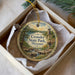 A decorative ornament in a box, featuring a scenic landscape with a waterfall and a lighthouse, with the text "Crowder State Park, Missouri" printed on it.