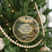 A round ornament hanging on a Christmas tree, featuring a scenic landscape with a waterfall and a tower.