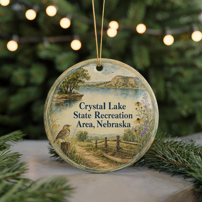 A round ornament with a scenic landscape depicting Crystal Lake State Recreation Area, Nebraska, featuring a bird, a boat, and a path.