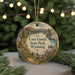 A round ornament with a scenic landscape of mountains, trees, and a river, featuring a bird and a deer, is displayed in front of a blurred background with twinkling lights.