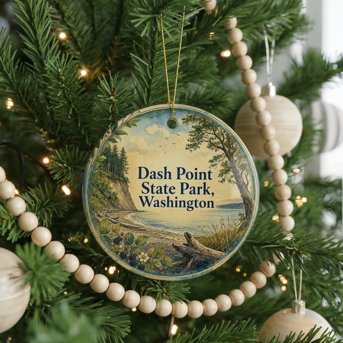 A circular ornament hanging on a Christmas tree, featuring a scenic landscape with a body of water and trees.