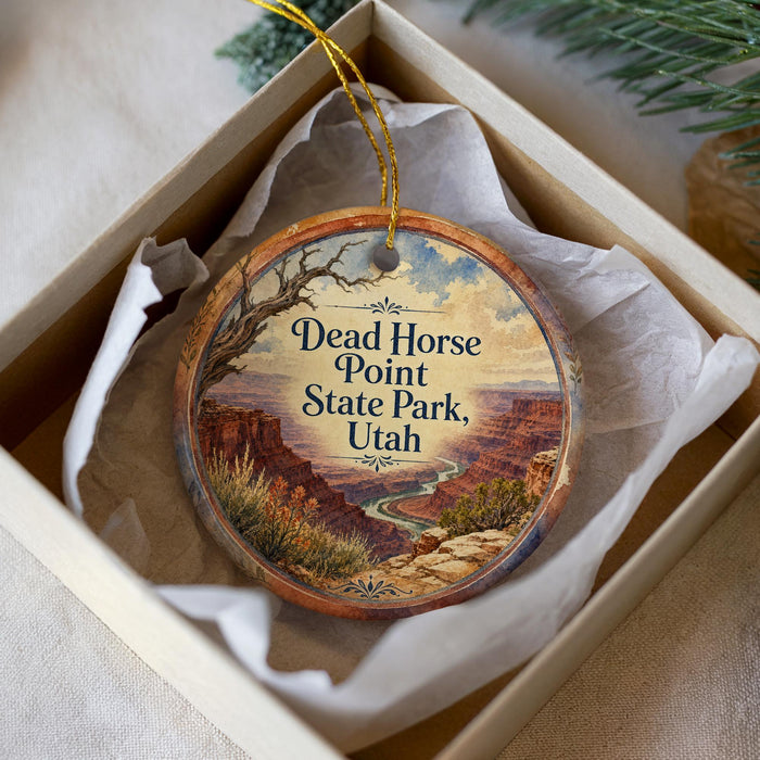 An oval ornament hanging from a string, featuring a scenic landscape of mountains and a winding river.
