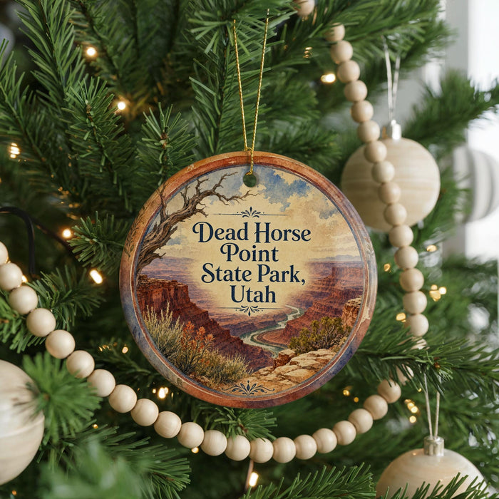 A circular ornament hanging on a Christmas tree, featuring a scenic image of the Dead Horse Point State Park in Utah.