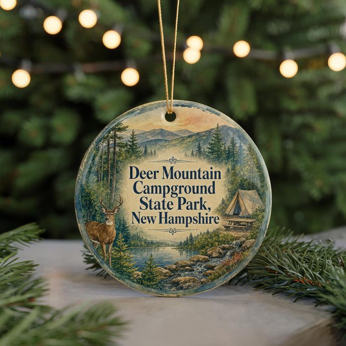 A round ornament with a painting of a deer in a forest, surrounded by Christmas lights and greenery.