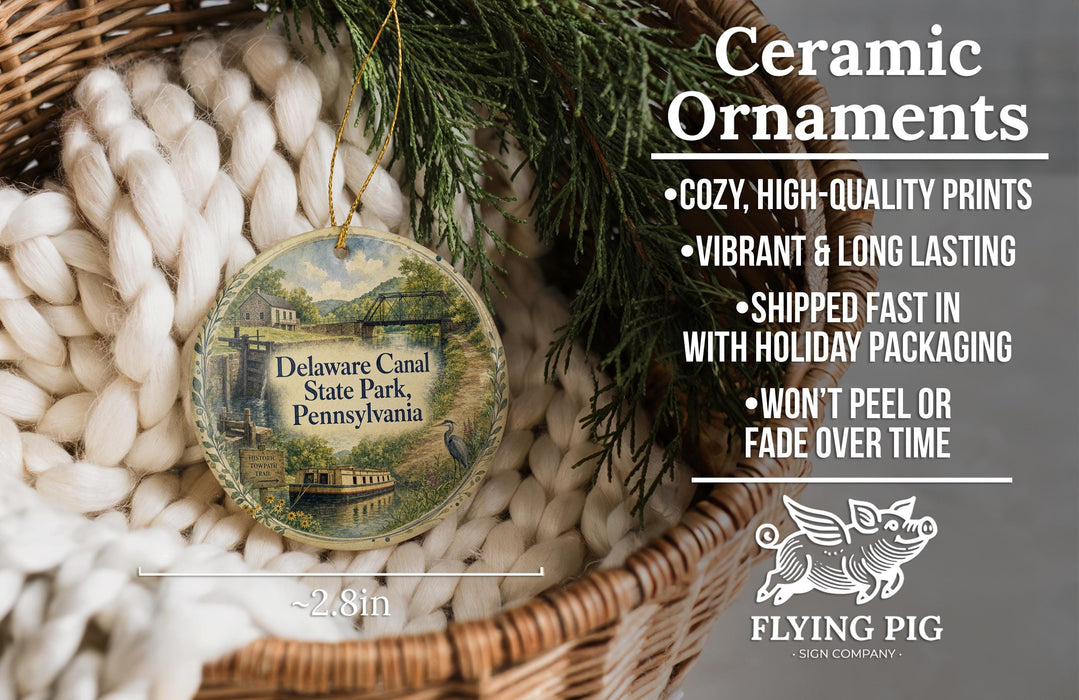 Ceramic ornaments, specifically a Delaware Canal State Park ornament, are displayed in a basket. The ornament features a scenic image of the canal and park, and it is described as a cozy, high-quality print, vibrant, and long-lasting. It is shipped fast in holiday packaging and does not peel or fade over time. The ornament is approximately 2.8 inches in diameter.