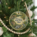 A round ornament hanging on a Christmas tree, featuring a scenic landscape with a waterfall and a bird in the foreground.