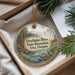A decorative ornament with a scenic landscape of a river, mountains, and pine trees, hanging from a string.