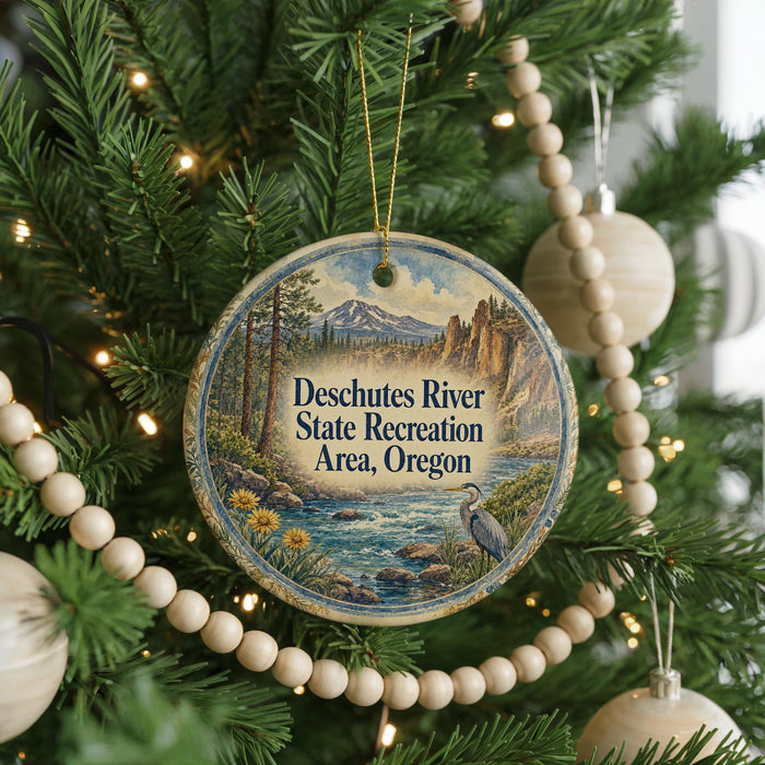 A round ornament hanging on a Christmas tree, featuring a scenic image of the Deschutes River State Recreation Area, Oregon.