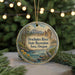A circular ornament with a scenic landscape depicting a river, mountains, and trees, hanging from a string.