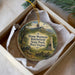 A decorative ornament in a box, featuring a scenic landscape with a monument and a cannon, along with text that reads " Droop Mountain Battlefield State Park, West Virginia".