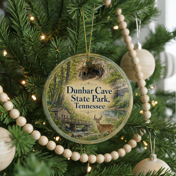A circular ornament hanging on a Christmas tree, featuring a scenic image of Dunbar Cave State Park, Tennessee.