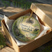 An ornament in a box, featuring a scenic image of Dunbar Cave State Park in Tennessee.