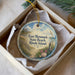 A decorative ornament in a box, featuring a beach scene with a wooden fence, seashells, and a bird in flight.