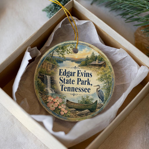 A round ornament with a scenic landscape of Edgar Evans State Park, Tennessee, featuring a waterfall, a boat, and a bird.