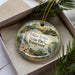 A decorative ornament with a scenic image of Edgar Evans State Park in Tennessee, featuring a waterfall, a boat, and pine trees.