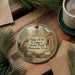 A round ornament with a scenic image of the Edge of the Cedars State Park Museum in Utah, featuring a mountain landscape and various objects.