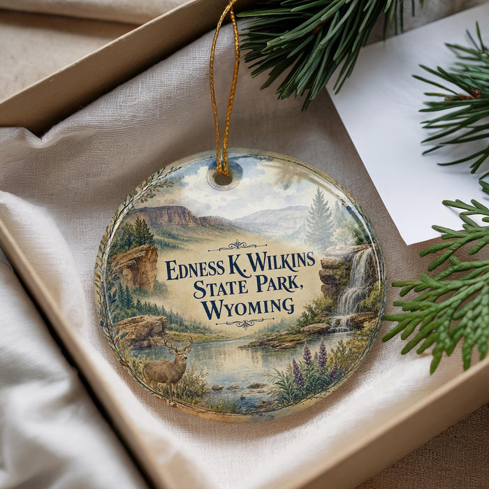 A decorative ornament with a scenic landscape of Edness K. Wilkins State Park, Wyoming, featuring a waterfall and pine trees.
