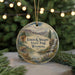 A decorative ornament featuring a scenic landscape with mountains, a waterfall, and a deer, hanging from a string.