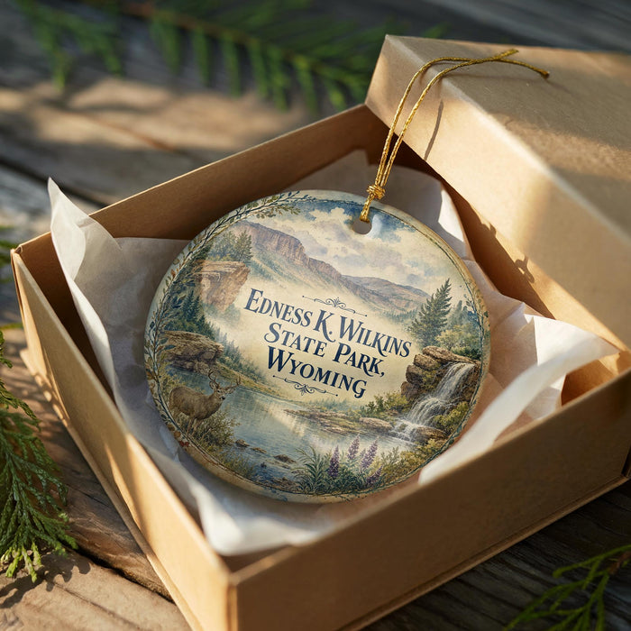 A decorative ornament in a wooden box, featuring a scenic landscape with mountains, waterfalls, and wildlife.