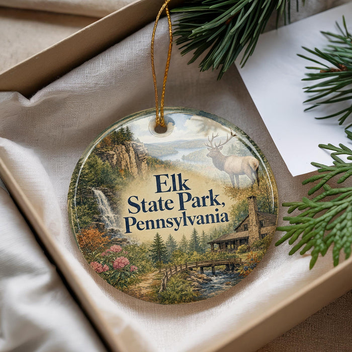 A decorative ornament with a scenic landscape of Elk State Park, Pennsylvania, featuring a deer, a waterfall, and a cabin.