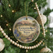 A circular ornament hanging on a Christmas tree, featuring a scenic landscape with mountains, cacti, and a blue sky.